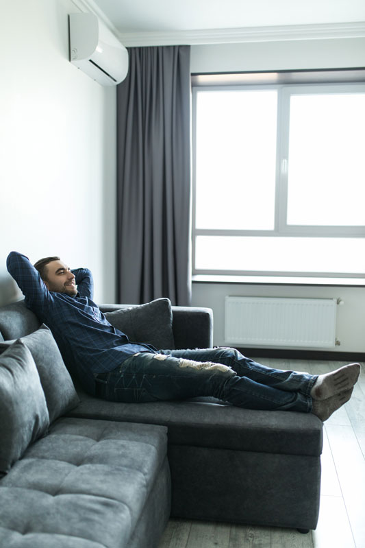 Man zit ontspannen op de bank en geniet van airco comfort in Haarlem