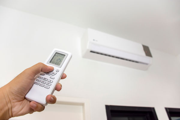 persoon bedient moderne airco met afstandsbediening in woning in Gouda